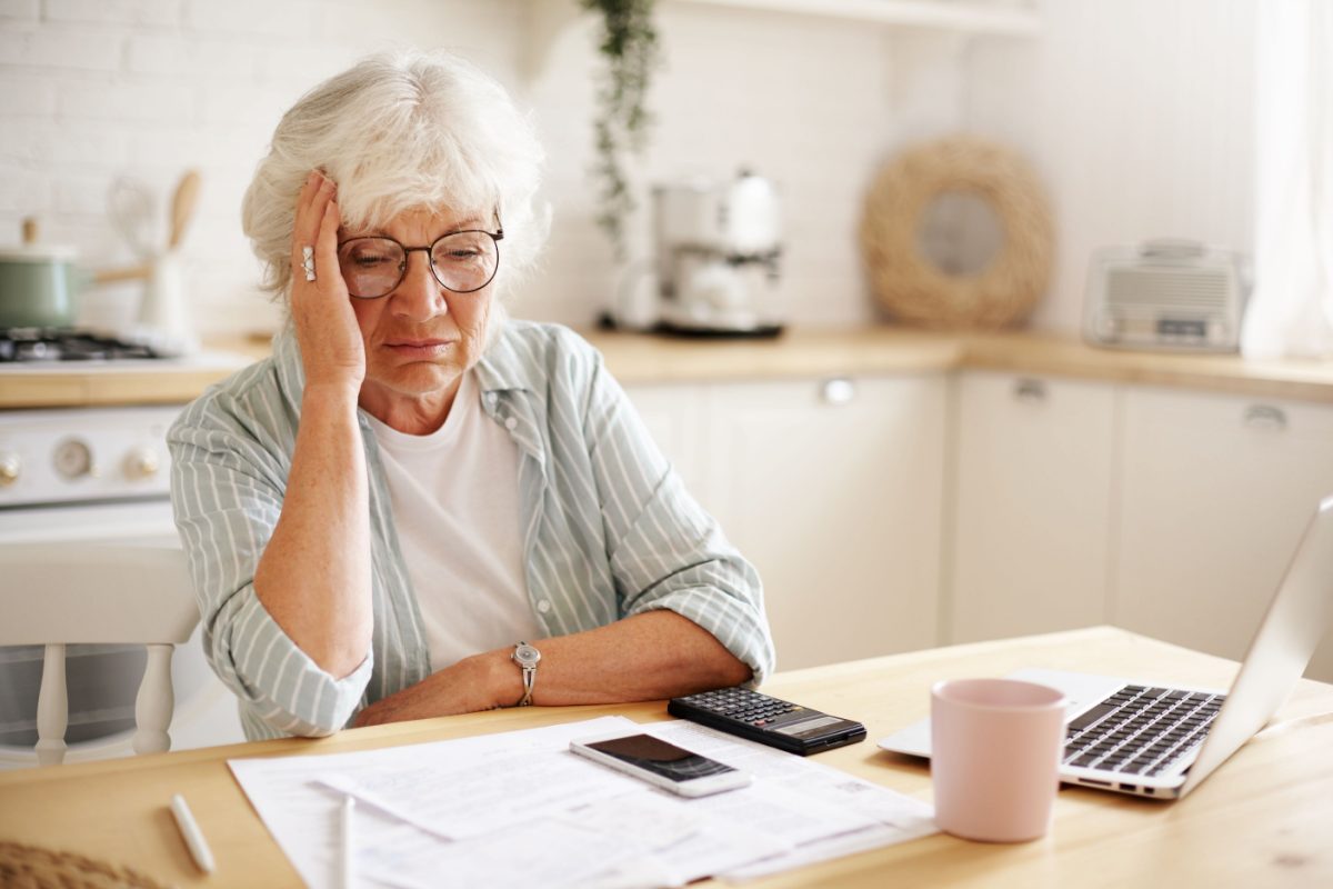 An older person working through claim paperwork at a kitchen table