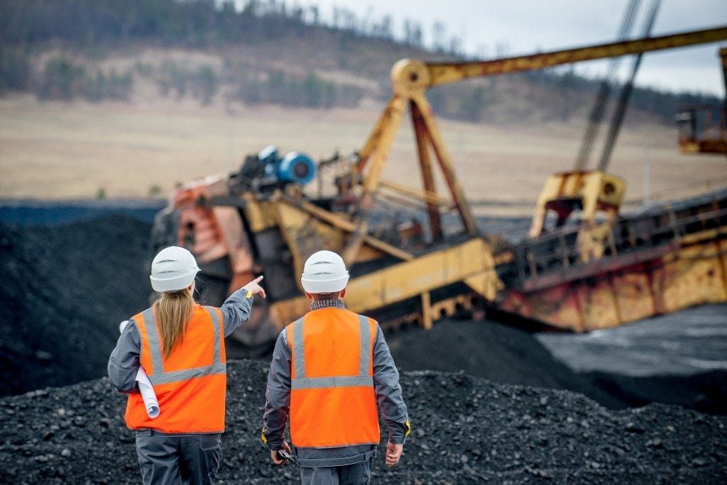 Two workers in high-visibility clothing at an open-cut mine